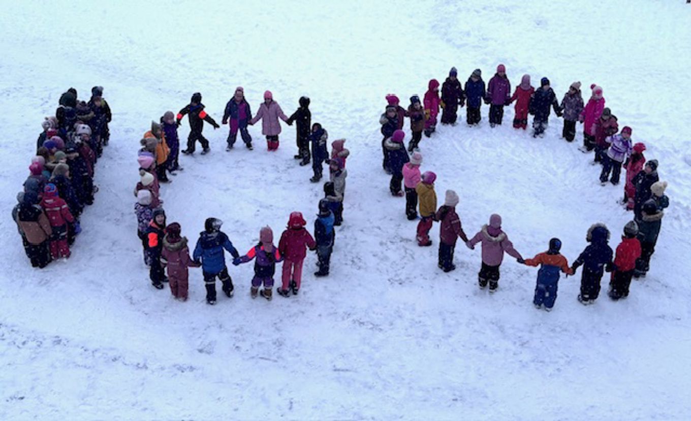 En gruppe mennesker på en snødekt bakke som former tallet 100