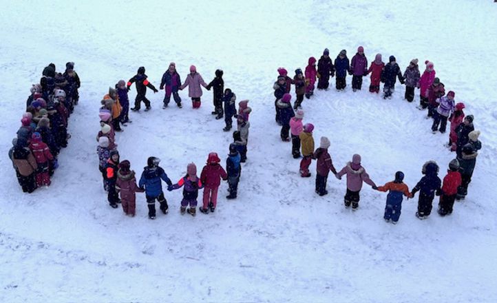 En gruppe mennesker på en snødekt bakke som former tallet 100